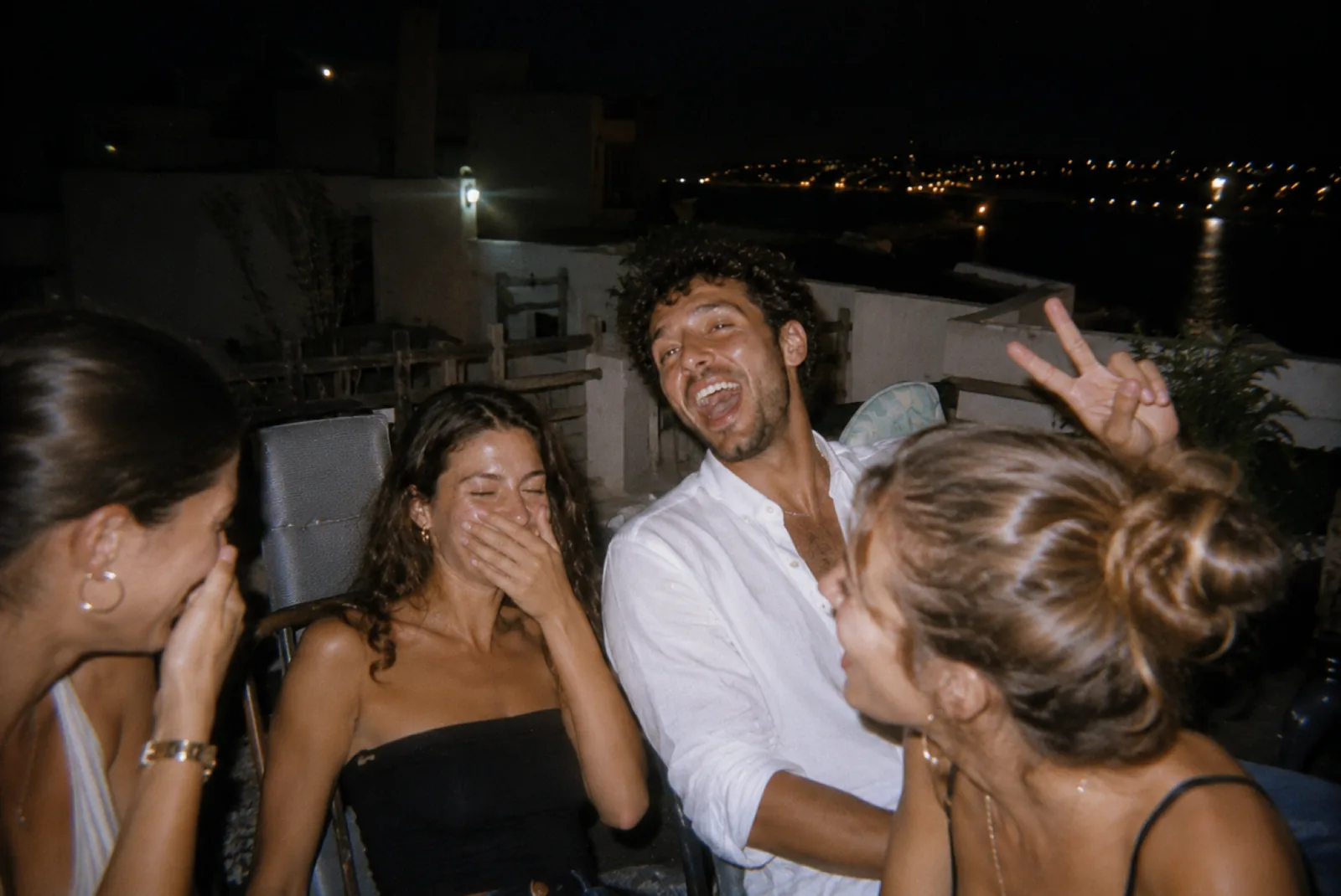 Quatre amis pris au flash en pleine crise de rire sur une terrasse de nuit