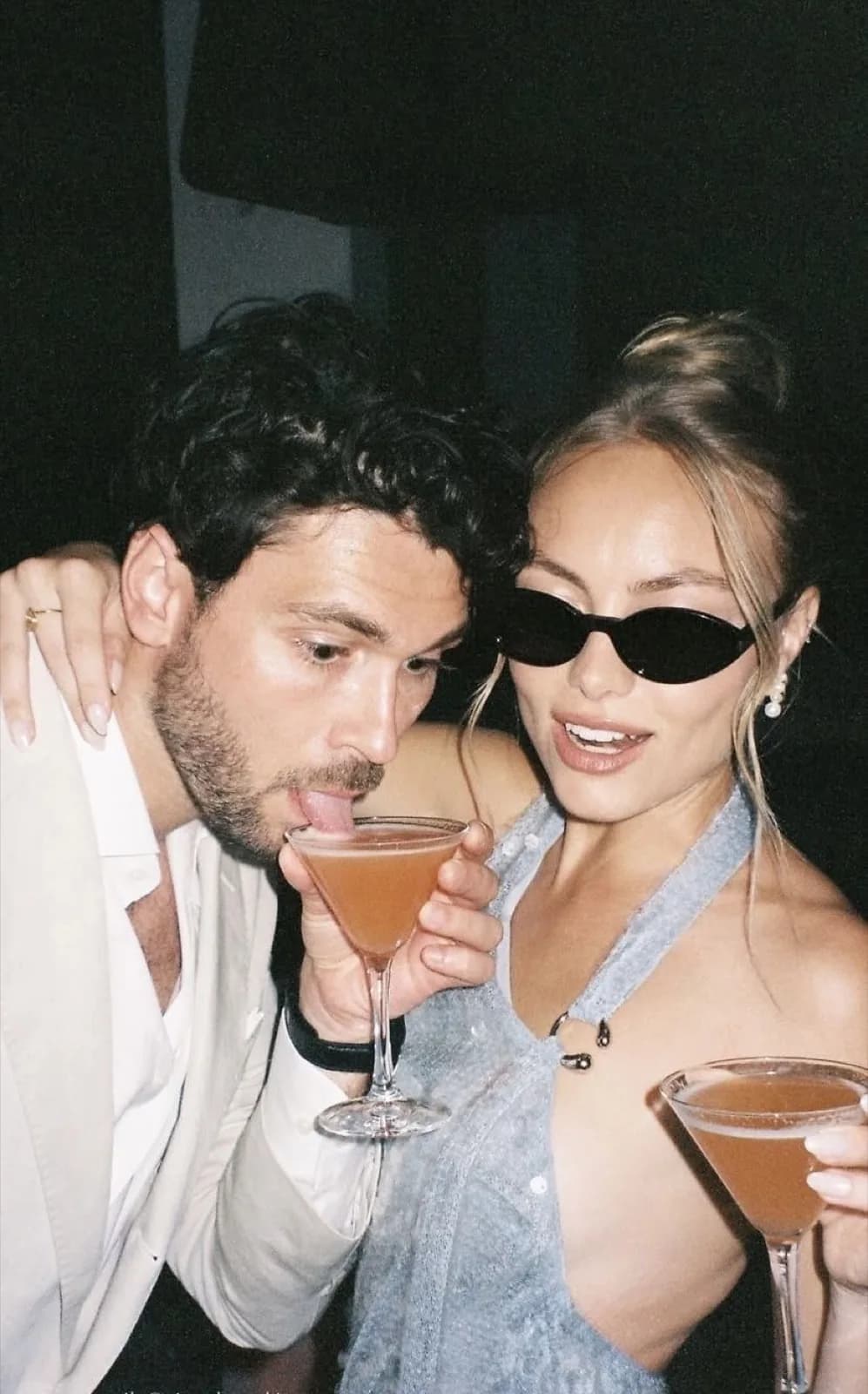 Couple au flash, deux coupes de cocktail levées en fin de soirée